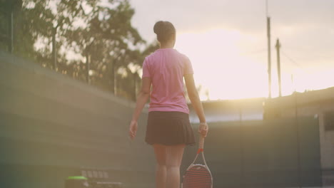 Rückansicht-Einer-Tennisspielerin,-Die-Bei-Sonnenuntergang-Mit-Einem-Schläger-Auf-Einer-Karte-In-Zeitlupe-Läuft